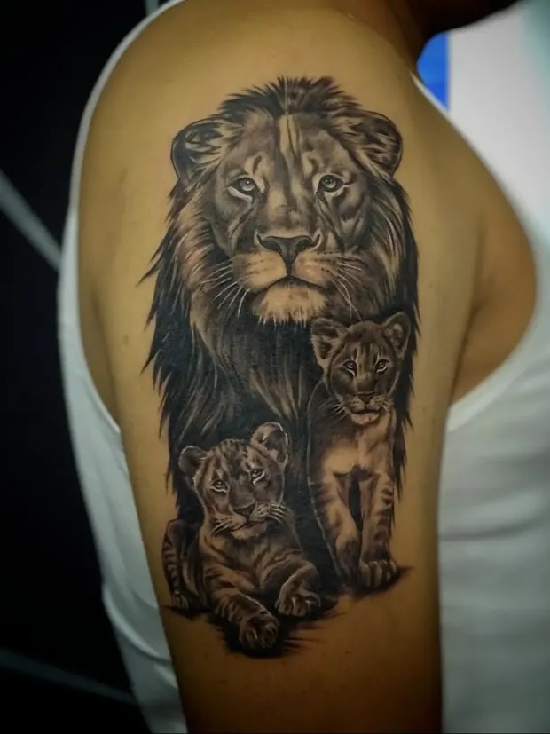 Tatuaje realista de un león con dos cachorros en el brazo